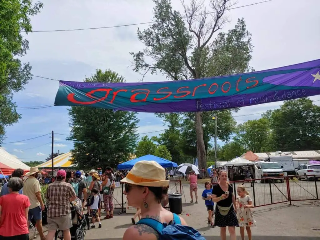 woman in hat in front of Grassroots festival entrance banner