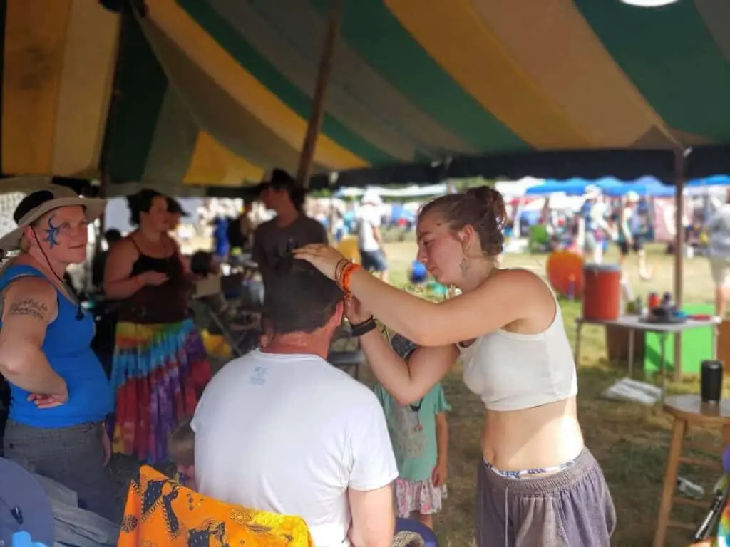 woman painting a man's face at festival