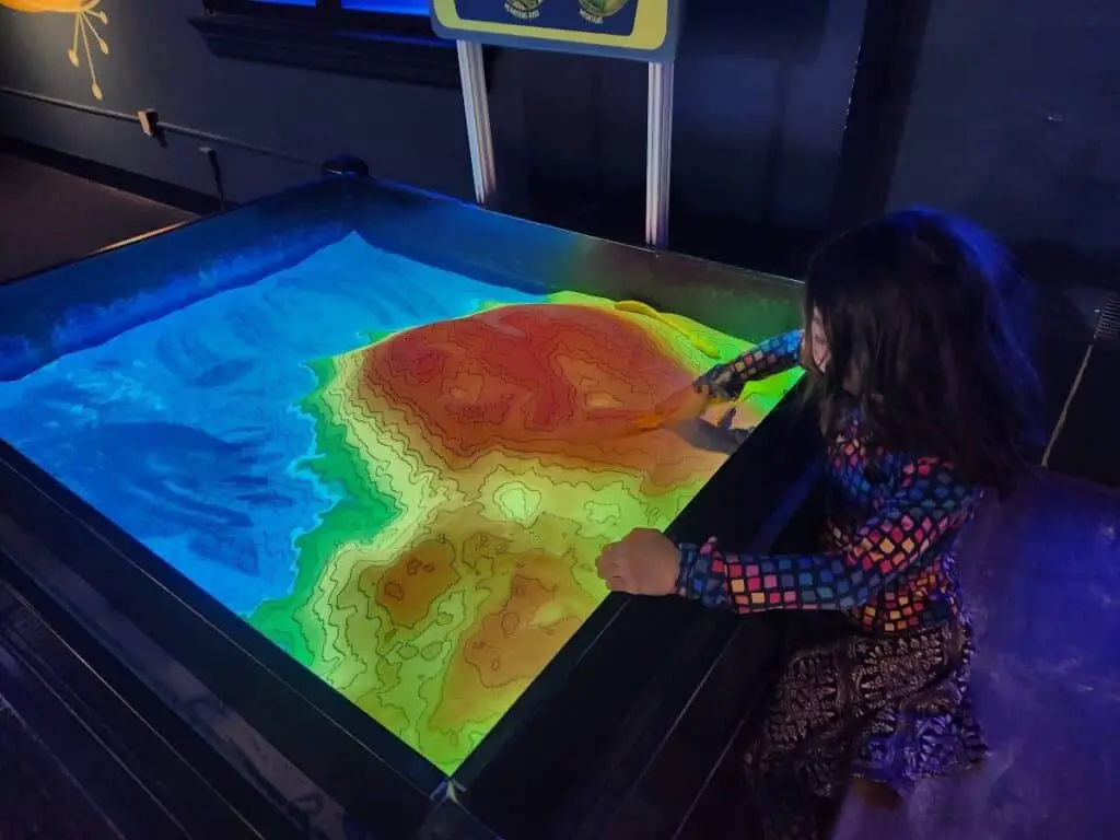 girl at colorful sand table