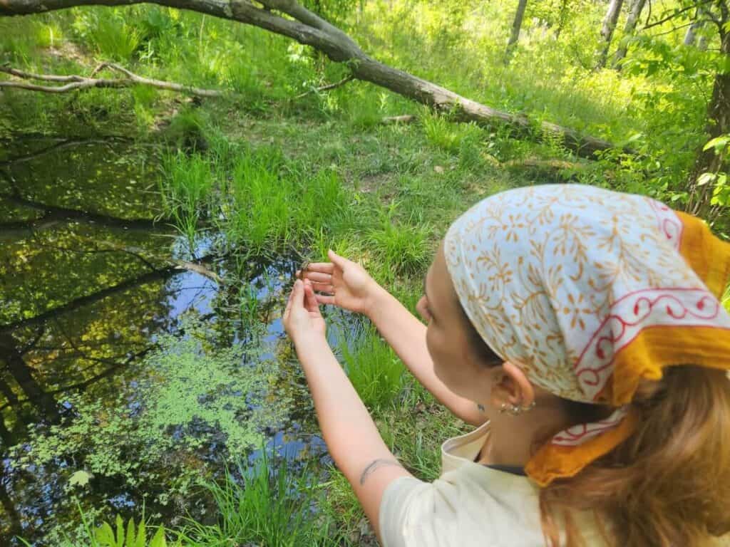 woman holding pickerel frog at pond